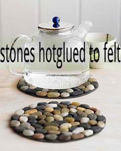 a glass tea pot and coaster on a table with rocks in front of it,