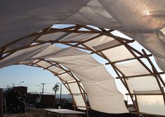 an outdoor covered area with chairs and tables under the shade from the sun shining through the fabric