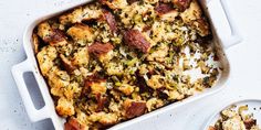 a casserole dish filled with stuffing next to a bowl of bread and vegetables