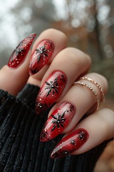 A classic red base with small star-shaped negative space designs outlined in black or gold for a celestial and modern look. White Red And Black Nails, Gold And Red Nails Acrylic, Red Black Silver Nails Design, Black And Red Snowflake Nails, Red Gold Black Nails, Black Red Gold Nails Art Designs, Black Nails With Red Foil, Constellation Nail Art, Red Nails Ideas