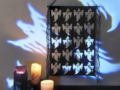 some candles are sitting on a table next to a black and white wallpaper with bats