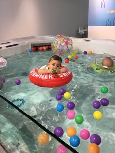 a baby sitting in an inflatable pool surrounded by balls and water toys on display