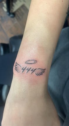 a person with a tattoo on their arm that has an angel wing and the word faith written in cursive writing