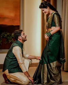 a man kneeling down next to a woman in a green and gold sari dress