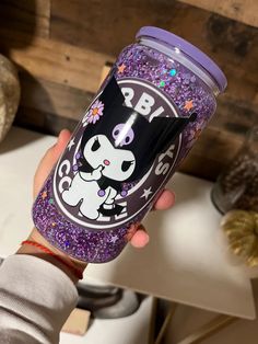 a person holding up a purple glitter tumbler with an animal on it's side