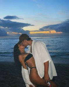 a man and woman kissing on the beach