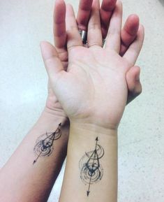 two hands holding each other with tattoos on them