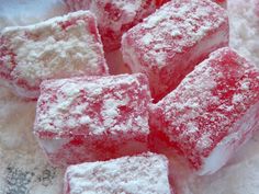 several pieces of red and white cake sitting on top of powdered sugar cubes