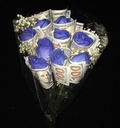 a bouquet of blue roses sitting on top of money