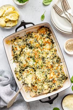 a casserole dish with spinach, cheese and other ingredients on the side