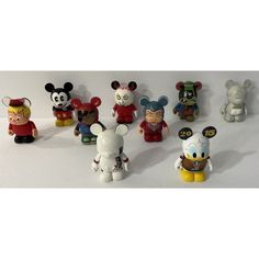 a group of mickey mouse figurines sitting on top of a white table next to each other