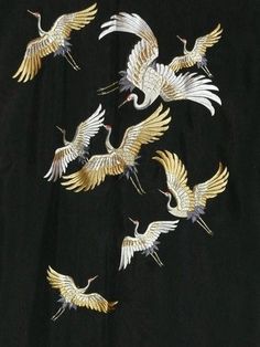 a black shirt with white and gold cranes on the front, flying in the air