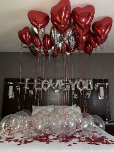 balloons and confetti on a bed with the word love you spelled in red