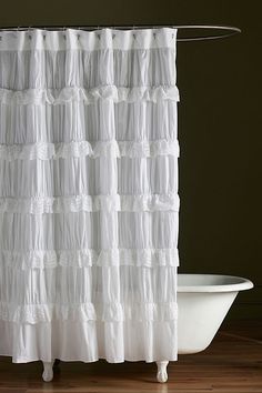 a white shower curtain sitting on top of a bath tub