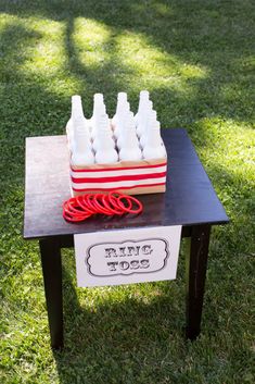 a table topped with plastic bottles and scissors on top of a grass covered field next to a red pair of scissors