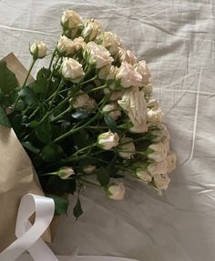 a bouquet of white roses is wrapped in brown paper and tied with a white ribbon