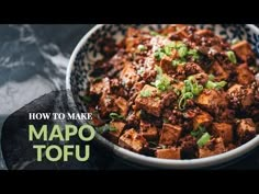 a bowl filled with tofu and green onions on top of a black tablecloth