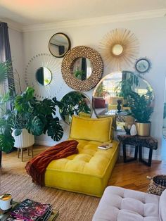 a living room filled with furniture and lots of mirrors on the wall above it's windows