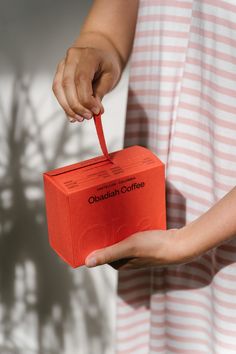 a person holding an orange box with the word canadian coffee on it in their hand