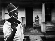 a man holding a book in front of a house