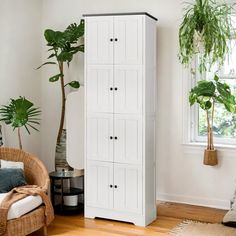 a tall white cabinet next to a potted plant in a living room with hardwood floors