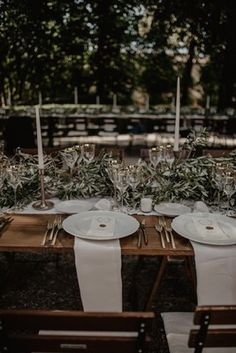 the table is set with white plates and silverware for an elegant dinner party or wedding reception