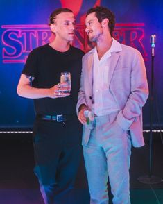 two men standing next to each other in front of a stage with microphones on it