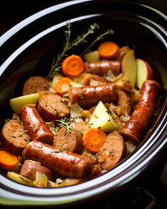 a crock pot filled with sausage, potatoes and carrots