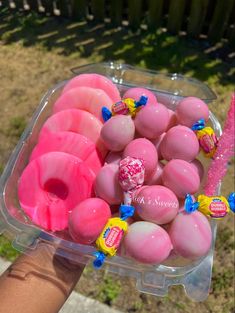 a plastic container filled with pink donuts and candy