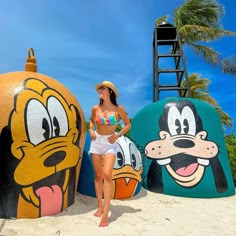 a woman standing in front of cartoon characters on the beach with palm trees behind her