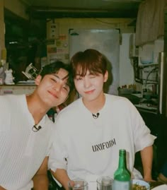 two young men sitting at a table with drinks