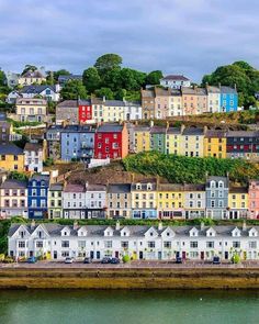 the colorful houses are on top of the hill by the water in front of them