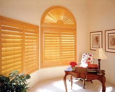 a living room filled with furniture and windows covered in wooden shutters, next to a potted plant