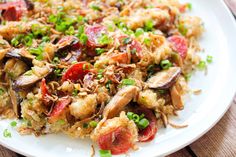 a white plate topped with rice covered in meat and veggies on top of a wooden table