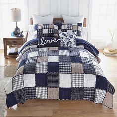 a bed with blue and white checkered comforter set on top of wooden flooring