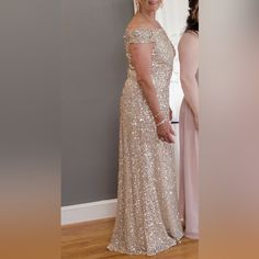 a woman in a gold dress standing next to another woman wearing a pink dress and smiling