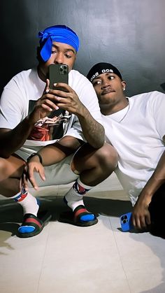 two men sitting on the floor taking a photo with their cell phone and wearing headbands