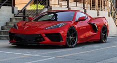 a red sports car parked in front of a set of stairs on the side of a building