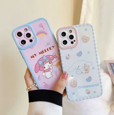 a person holding two cell phones with hello kitty cases on their covers, one is pink and the other is blue