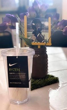 a plastic cup sitting on top of a table next to a vase filled with flowers