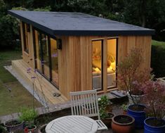 a small wooden house with patio furniture and potted plants in the back yard area