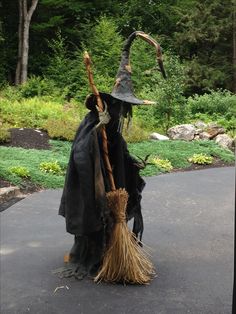 a scarecrow dressed in black holding a broom