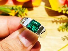 a person holding a ring with a green stone in it