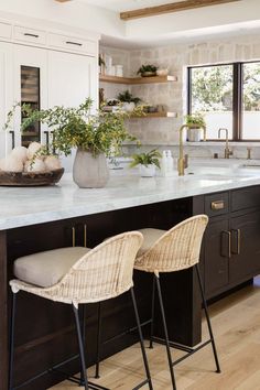 two chairs sitting on top of a kitchen counter next to an island with plants in it