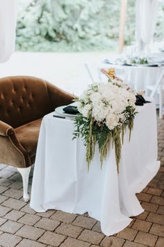 a table with white flowers and greenery is set up for an outdoor wedding reception