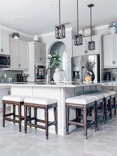 a kitchen with white cabinets and stools next to an island in the middle of the room