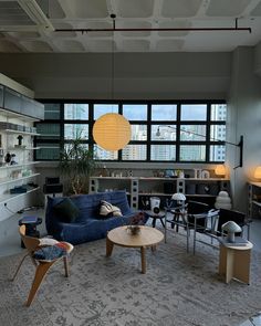 a living room filled with lots of furniture and large windows in the back drop down ceiling