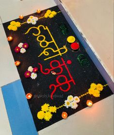 a decorated black mat with flowers and candles on it that says happy holi diwal