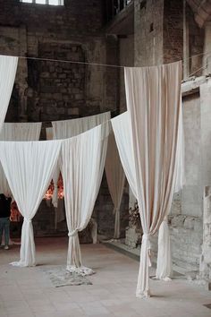 several white drapes are hanging in an old building