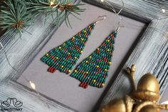 These Christmas tree beaded earrings are made of high-quality Czech beads and metal components. They are elegant, fashionable, and highly versatile, suitable for everyday wear.Features:Sterling silver hooksColor: 2 shades of green, gold, yellow, red, blue, brownLength: 8 cm (3.14 in)This item is currently in stock.More beaded earrings http://etsy.me/2ycItdb Gerdan necklaces http://etsy.me/2mihf0JBeaded necklaces http://etsy.me/2Dkf1FoCrochet necklaces http://etsy.me/2CAPdFcBack to shop https://w Christmas Tree Beads, Miyuki Beads Pattern, Fringe Earring, Gold Chandelier Earrings, Beadwork Necklace, Long Gold Earrings, Earrings Christmas, Earrings Green, Miyuki Beads